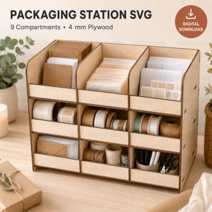 Peut inclure: Un organisateur de station d'emballage en bois clair comportant neuf compartiments conçus pour du contreplaqué de 4 mm. L'unité contient divers articles de papeterie, dont des enveloppes, des rouleaux de ruban adhésif, de la ficelle et des fournitures de bureau, avec le texte PACKAGING STATION SVG et 9 Compartments • 4 mm Plywood visible.