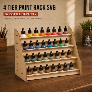 May include: A four-tier wooden paint rack with a 32-bottle capacity, featuring laser-cut slots holding various coloured paint bottles. The text 4 TIER PAINT RACK SVG, 32 BOTTLE CAPACITY, and LASER CUT FILE DIGITAL DOWNLOAD are visible above the rack.