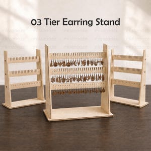 May include: Three light-colored wooden 03 Tier Earring Stand displays. The central stand features three horizontal bars with numerous small slots, holding rows of dangling brown wooden earrings in various shapes like pumpkins and stars.