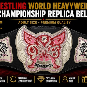 May include: A black leather replica wrestling championship belt featuring a large central plate with the word Divas and the word Champion below it. The plates are made of 2mm brass with pink and red accents and decorative crystal embellishments.