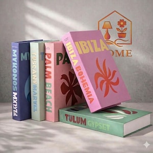 Op de afbeelding: Een verzameling decoratieve boeken in verschillende kleuren, waaronder paars, lichtgroen, roze en lichtbeige. De boeken bevatten teksten als "Mykonos", "Tuscany Marvel", "Palm Beach", "Ibiza Bohemia" en "Tulum Gypset". De boeken hebben een tropisch thema.