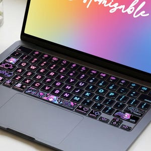 May include: A gray laptop with a colorful screen displaying the word "Customizable". The keyboard has decorative stickers. A small vase of flowers, a bunny figurine, and a cup of tea are on the table. The text "Art Nathaniel" is at the bottom.