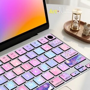 Op de afbeelding: Een laptoptoetsenbordhoes met een pastelkleurig verloop van roze, blauw en paars. De toetsen zijn versierd met kleine iconen zoals hartjes, sterretjes en bloemen. Specifieke toetsen tonen illustraties van een popcornemmer, een envelop en een kasteel.