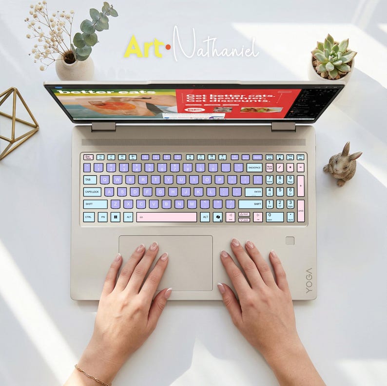 K&ouml;nnte beinhalten: Ein beigefarbener Laptop mit einer individuellen Tastaturfolie in Helllila, Hellblau und Hellrosa. Auf dem Bildschirm ist eine Website mit dem Text 'better eats' und 'Get better eats. Get healthier. Get discounts.' zu sehen. Das Logo 'Art-Nathaniel' ist sichtbar.