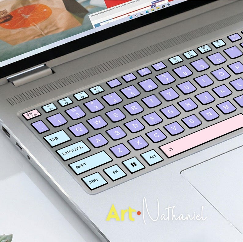 K&ouml;nnte beinhalten: Ein silberner Laptop mit einer individuellen Tastaturabdeckung im Color-Blocking-Design. Die Tasten sind in Hellblau, sanftem Violett und Blassrosa gehalten und mit schwarzer Schrift versehen. Das Layout umfasst Standard-QWERTY-Tasten.