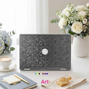 Op de afbeelding: Een Dell-laptop met een donkergrijs, gestructureerd marmerpatroon op het deksel. De laptop is centraal geplaatst en toont het witte Dell-logo in het midden. Onder de laptop geeft een rij kleine gekleurde cirkels de kleuropties aan.