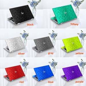 Op de afbeelding: Een collectie van acht laptopskins met een textuur van gekreukt fluweel in zwart, Tiffany-blauw, zilver, grijs, geel, rood, blauw en paars. Elke skin toont een centraal logo en is aangebracht op een laptop.
