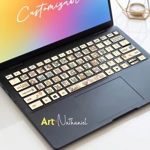 May include: A black laptop with keyboard stickers featuring colorful letters, numbers, and cartoon illustrations. The screen displays a rainbow gradient with the word "Customize" in white script. The laptop has the text "Art Nathaniel" in yellow and white.