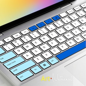 Pode incluir: Uma capa de teclado para portátil com layout QWERTY branco e letras pretas. As teclas tab, caps lock, shift, ctrl e fn são azul-claras, enquanto a linha superior de teclas de função é azul-escura. O texto Art Nathaniel é visível.