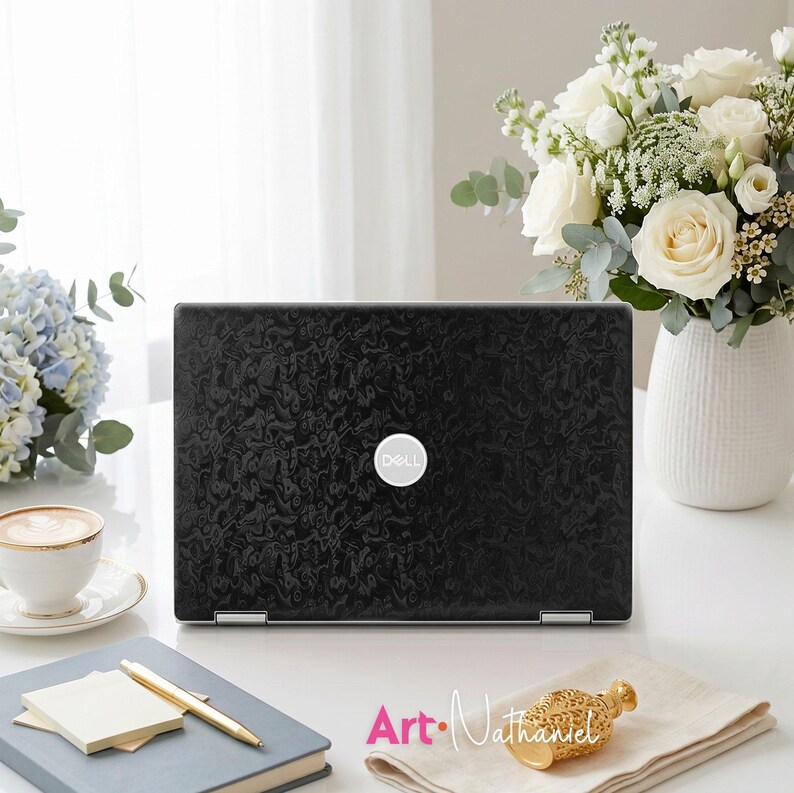 Op de afbeelding: Een zwarte Dell-laptop met een gestructureerd, wervelend patroon op de deksel. De laptop staat centraal en is voorzien van een zilverkleurig, rond Dell-logo in het midden. Het oppervlak van de deksel toont een donker, ingewikkeld abstract ontwerp.
