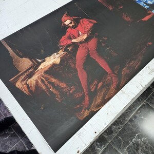 May include: A rectangular canvas print featuring a reproduction of Jan Matejko's Stańczyk painting. The artwork depicts a jester in a red costume sitting in a dark, somber room with a letter on a table. Additional small art prints are visible at the top.