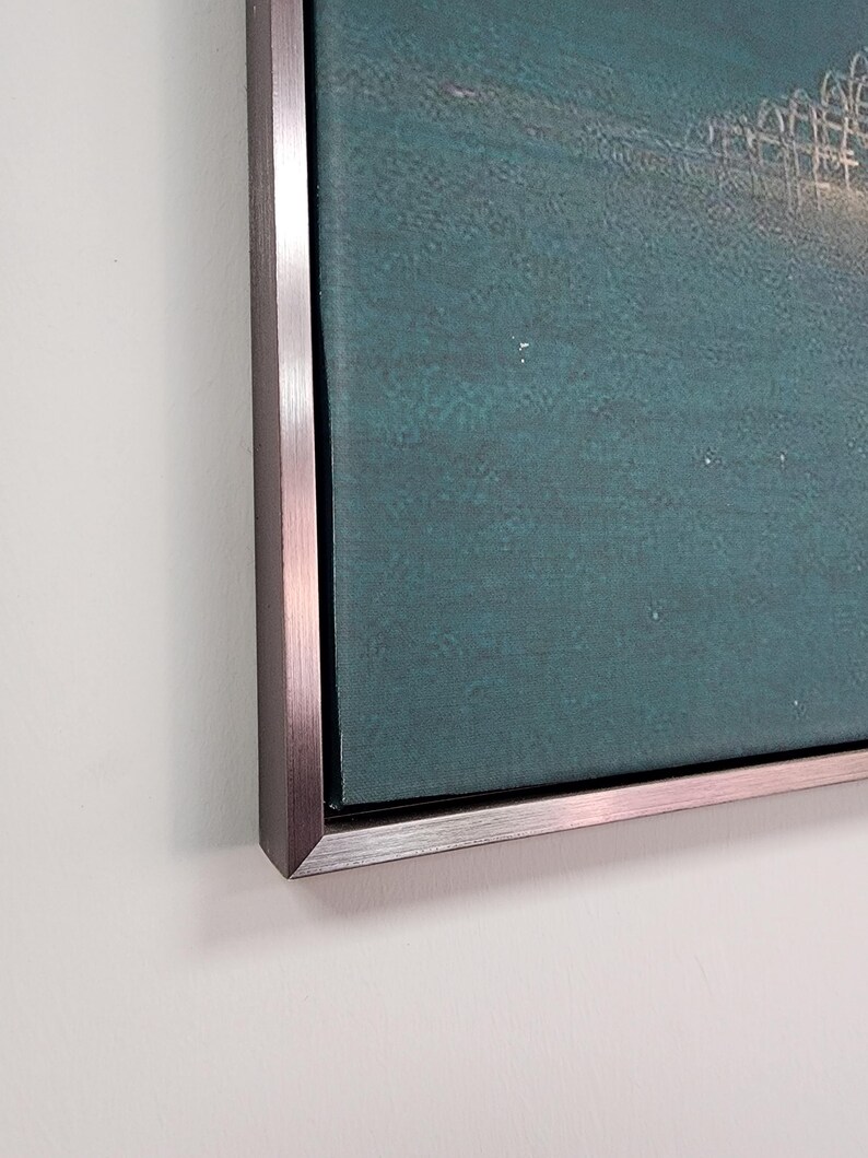 May include: A rectangular wall art piece featuring a deep teal canvas with a subtle textured surface. The artwork is encased in a metallic, brushed silver-toned frame with a clean, sharp edge, providing a modern and structured border.