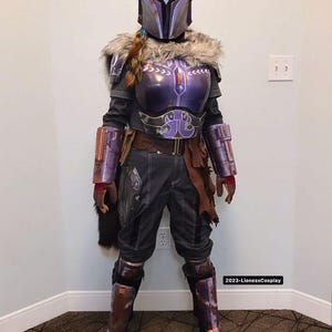 May include: A full-body shot of a detailed cosplay costume. The costume features a purple helmet, chest armor, and arm guards with silver accents. The outfit includes a fur collar, dark pants, and boots. The overall design suggests a futuristic or sci-fi theme.