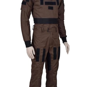 May include: Brown jumpsuit with black accents. The outfit features a high collar, long sleeves, and black patches on the chest, shoulders, and legs. A black belt cinches the waist. The jumpsuit is made of a durable fabric.