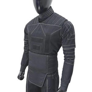 May include: Black tactical vest with white stitching, displayed on a mannequin. The vest features multiple panels, hook-and-loop closures, and long sleeves. The mannequin is black and the background is white.