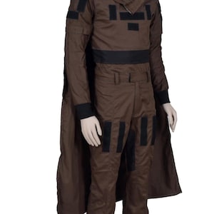May include: Brown costume with black accents, including a long-sleeved top, pants, and a cape. The top features a high collar and black patches. The pants have black patches on the knees. The costume is displayed on a mannequin.