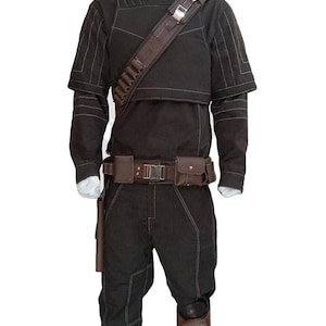 May include: A black costume with white stitching, featuring a high collar, long sleeves, and a cropped jacket. It includes a brown shoulder strap with pouches, a belt with a buckle, and matching pants. The costume has knee pads and a holster.
