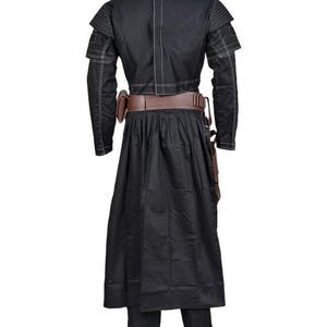 May include: Black costume with white stitching details. The outfit includes a long-sleeved jacket with shoulder accents, a long skirt, and matching pants. A brown belt and pouches complete the ensemble. The costume is designed for cosplay or themed events.