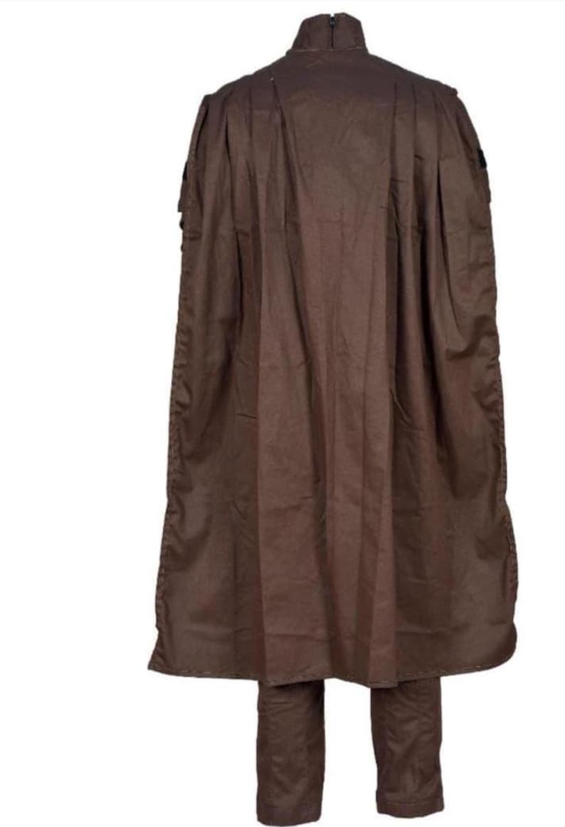 May include: A brown two-piece outfit, featuring a long-sleeved top with a high collar and a matching pair of pants. The top has a cape-like design that extends down the back. The outfit is made of a solid, dark brown fabric.