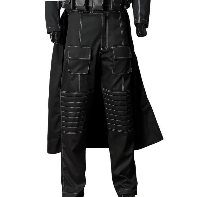 May include: Black tactical pants with white stitching details. The pants feature multiple pockets and reinforced knee panels. A black coat is visible in the background. The pants are part of a costume or uniform.
