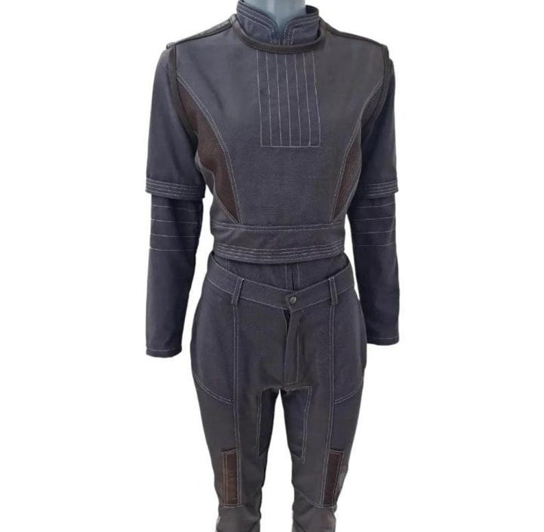 May include: A two-piece outfit in shades of gray and brown. The top has a high collar, long sleeves, and a fitted waist. The pants are high-waisted with pockets and a button closure. White stitching details the seams. The outfit is displayed on a mannequin.