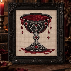 May include: A cross-stitch embroidery piece framed in a black ornate frame, depicting a silver chalice filled with a deep red liquid that overflows and drips down the sides, with a pool of the same red liquid at the base of the chalice stem.