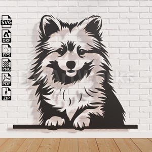 Puede incluir: Arte de pared de metal negro de un perro Pomerania. El perro está representado en un diseño estilizado y recortado, con detalles de pelaje y una expresión sonriente. La obra de arte está montada en una pared de ladrillo blanco.