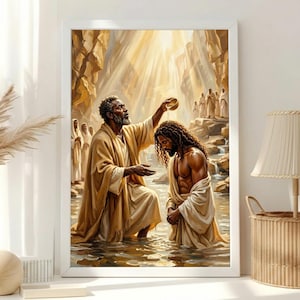 May include: A framed wall art print depicting a baptism scene in a rocky river. An older figure in tan robes pours water from a small bowl onto the head of a younger figure with long dark hair. Other figures stand in the background under golden light.