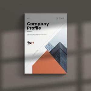 May include: A white Company Profile document with the year 2027 in orange. The cover features a geometric design with an orange triangle and a building illustration. The document is on a grey surface.