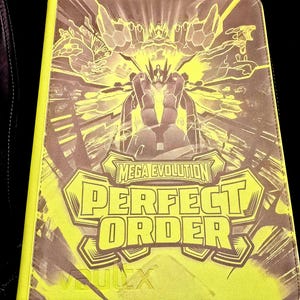 May include: A rectangular trading card binder with a bright neon yellow border and a dark brown cover. The cover features a central graphic of a stylized robotic figure with the text "MEGA EVOLUTION" and "PERFECT ORDER" printed in bold letters.