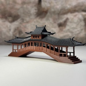 Könnte beinhalten: Eine Miniaturbrücke im asiatischen Stil in Braun und Schwarz mit einem mehrstufigen Dach. Die Brücke hat ein detailliertes Design mit Stufen, die zum Gehweg führen. Das Dach ist schwarz mit aufwendigen Details.