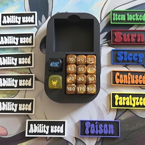 Könnte beinhalten: Ein schwarzes Spielzubehör-Tablett aus Kunststoff mit einem schwarzen Würfel mit der Aufschrift ex, einem durchscheinend gelben Würfel mit Pikachu-Gesicht und zwölf braunen Würfeln mit den Zahlen 10 bis 180. Enthält sechs Ability used-Marker.