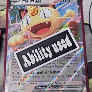 Könnte beinhalten: Eine Pokémon-Sammelkarte mit Mauzi ex und 170 KP. Die Karte hat eine farbenfrohe Illustration der Figur und den Text "Ability Used" auf einem schwarz-weißen Aufkleber. Die Karte hat einen roten Rand.