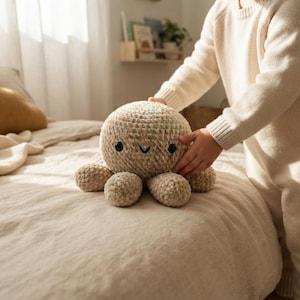 Peut inclure: Une peluche pieuvre en crochet beige avec une tête ronde, huit tentacules courts et deux petits yeux en plastique noir. Le jouet présente une surface en fil texturé et une bouche cousue simple, fabriqué dans un matériau doux aux tons neutres.