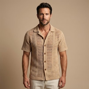 Peut inclure: Une chemise en crochet beige à manches courtes et à boutons. La chemise a un col et un motif ajouré texturé. Les boutons sont de couleur beige assortie. La chemise est portée avec un pantalon clair.