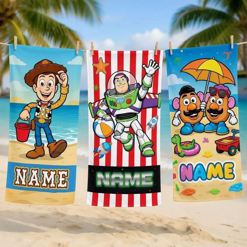 K&ouml;nnte beinhalten: Drei Strandt&uuml;cher h&auml;ngen an einer W&auml;scheleine. Jedes Handtuch zeigt eine andere Zeichentrickfigur: Woody, Buzz Lightyear und Mr. Potato Head. Jedes Handtuch hat unten einen Platz f&uuml;r einen Namen.