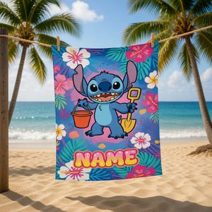 May include: Blue beach towel featuring the character Stitch from Lilo & Stitch, holding a bucket and shovel. The towel has a tropical floral pattern with the word "NAME" in a bubble font. The background shows a beach scene with palm trees.