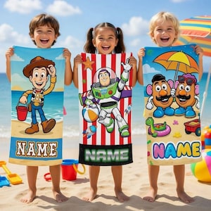 K&ouml;nnte beinhalten: Drei Kinder am Strand halten bunte Strandt&uuml;cher. Jedes Handtuch zeigt eine andere Zeichentrickfigur: Woody, Buzz Lightyear und Mr. Potato Head. Die Handt&uuml;cher haben unten einen personalisierten "NAME"-Bereich.