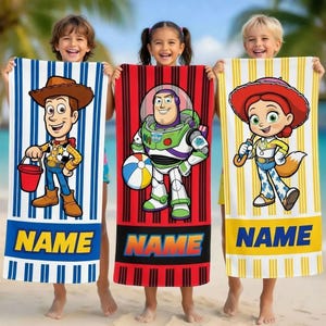 Pu&ograve; includere: Tre teli da mare con personaggi di Toy Story. Uno ha uno sfondo a righe blu e bianche con Woody. Un altro ha uno sfondo rosso con Buzz Lightyear. Il terzo ha uno sfondo a righe gialle e bianche con Jessie. Ogni telo ha la parola "NAME" in basso.