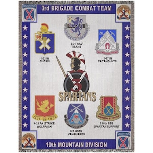 May include: A white and blue woven throw blanket featuring military unit insignias and the text "3rd BRIGADE COMBAT TEAM" and "10th MOUNTAIN DIVISION". The blanket has a fringed border and includes the word "SPARTANS".