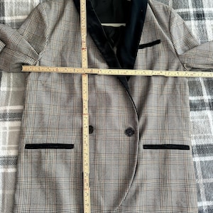 May include: A plaid blazer with a black velvet collar and pocket trim. The blazer has a double-breasted design with two buttons and two front pockets. The blazer measures approximately 30 inches in length.