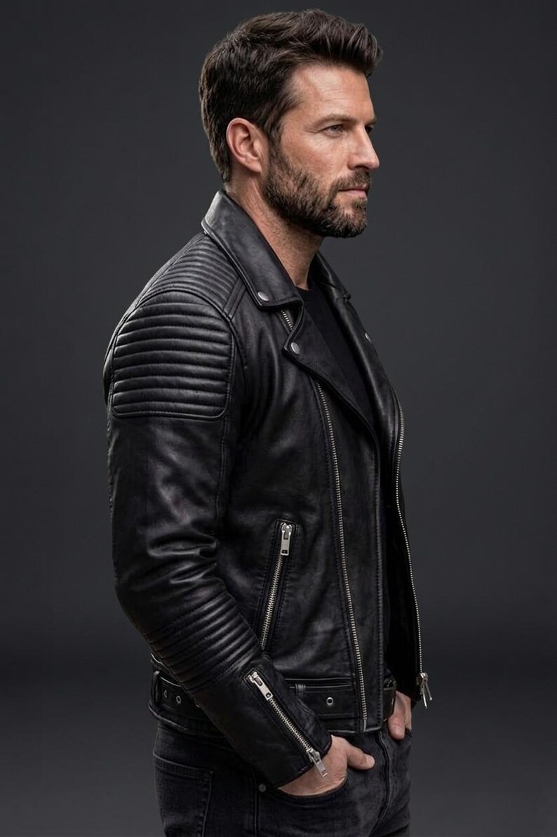 May include: A black leather motorcycle jacket featuring a notched lapel, silver-toned metal zips on the front and cuffs, and quilted padding details on the shoulders and upper sleeves. The jacket is worn over a plain black shirt and dark jeans.