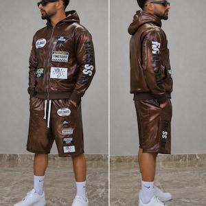 May include: A brown faux leather hoodie and shorts set. The jacket has multiple patches and the text "FINESSER" on the sleeve. The shorts also have patches and the text "FINESSER" on the leg. The set is worn with white trainers and socks.