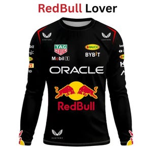 May include: Black long-sleeve shirt with the text "RedBull Lover" at the top. The shirt features the Red Bull logo, sponsor logos, and the word "ORACLE" in white. The shirt has red and yellow accents.