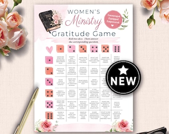 May include: A printed game sheet titled Women's Ministry Gratitude Game featuring a grid of questions, pink dice illustrations, a black Bible graphic, and floral accents. A black circular badge with a white star and the text NEW is overlaid.