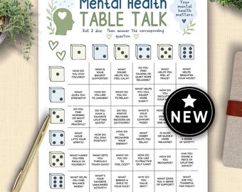 May include: A white Mental Health Table Talk sheet with a dice game format. The sheet includes questions about mental well-being and a "NEW" sticker. A gold pen rests on the table next to the sheet.