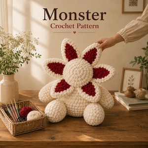 May include: A cream-colored crochet monster plush with a large, flower-like head featuring dark red petal accents. The creature has a round body and two rounded feet. The text "Monster Crochet Pattern" is displayed above the plush toy.