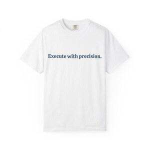 May include: White t-shirt with the text "Execute with precision" in navy blue. The shirt has a crew neck and short sleeves. The fabric appears to be a soft, comfortable material.