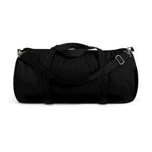 May include: A black duffel bag with a shoulder strap and two handles. The bag is cylindrical and appears to be made of a durable fabric. The shoulder strap is adjustable and has metal clips. The bag is designed for carrying sports gear or travel items.