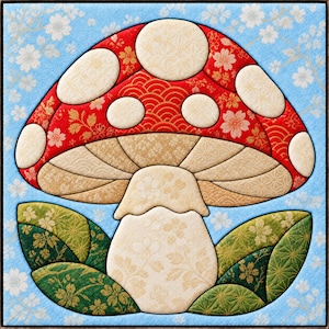 May include: A square fabric art piece featuring a central mushroom with a red cap adorned with cream-colored circular spots. The mushroom has a tan underside and a cream stem, surrounded by green leaves against a light blue floral background.